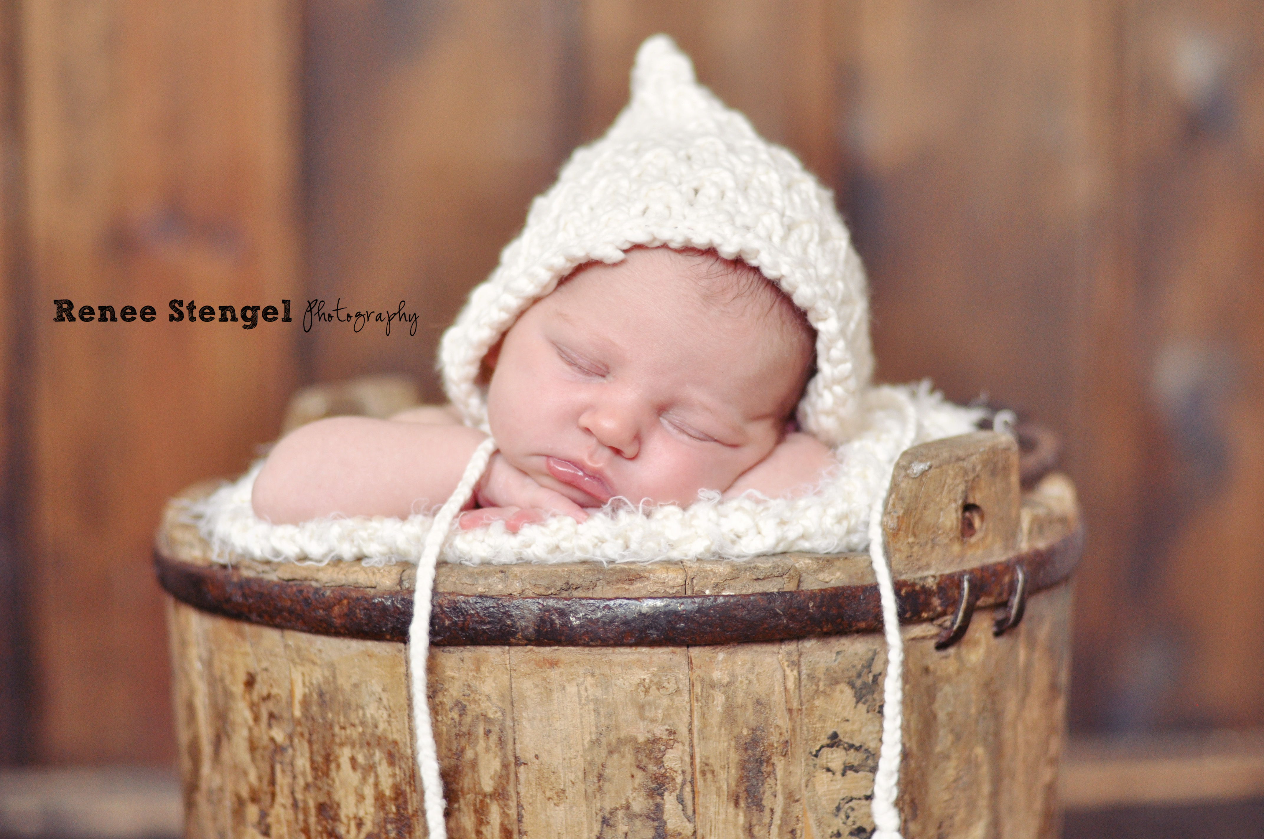 Newborn Baby with cream bonnet in bucket