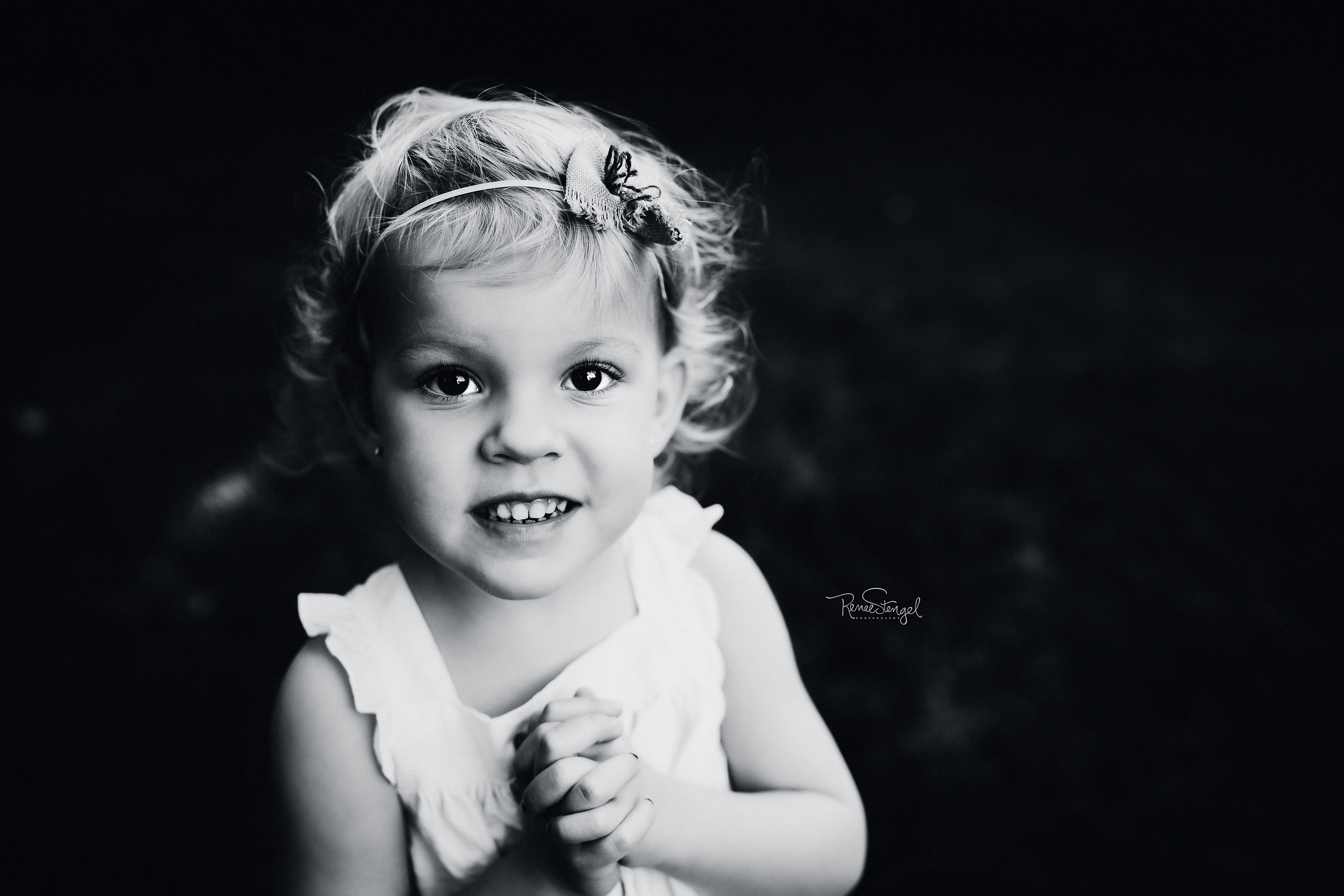 Black and White Portrait of three year old baby girl with blond curls in organic cotton dress