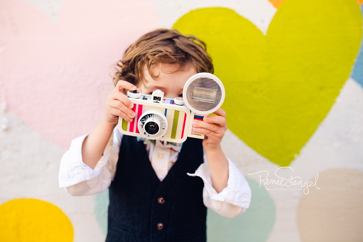 Cool Toddler with Camera at Charlotte's Confetti Hearts Wall by Evelyn Henson