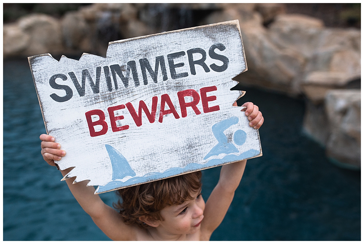 Swimmers Beware Shark Sign held by little boy next to Charlotte Underwater Studio Pool