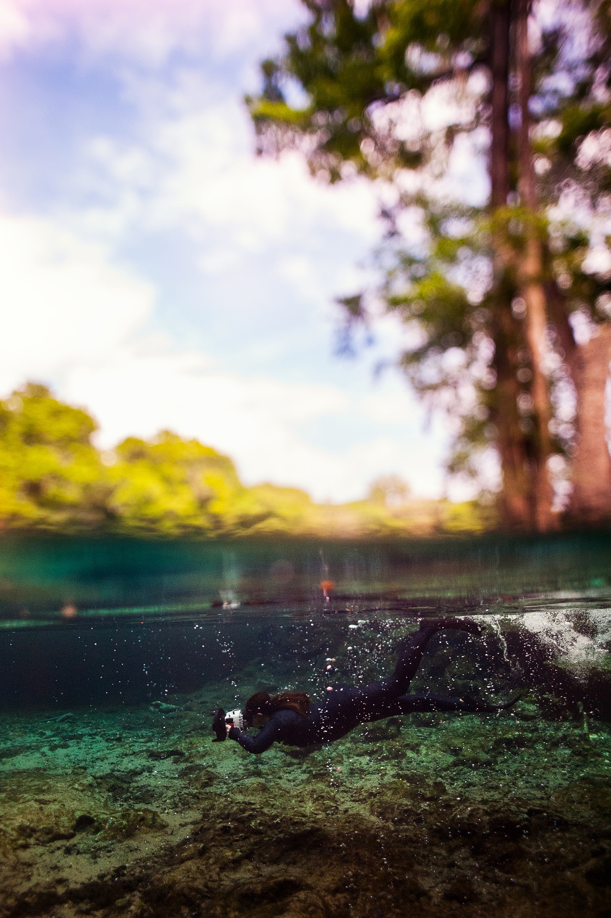 Charlotte Underwater Photographer Freediving in natural springs with green water and blue skies