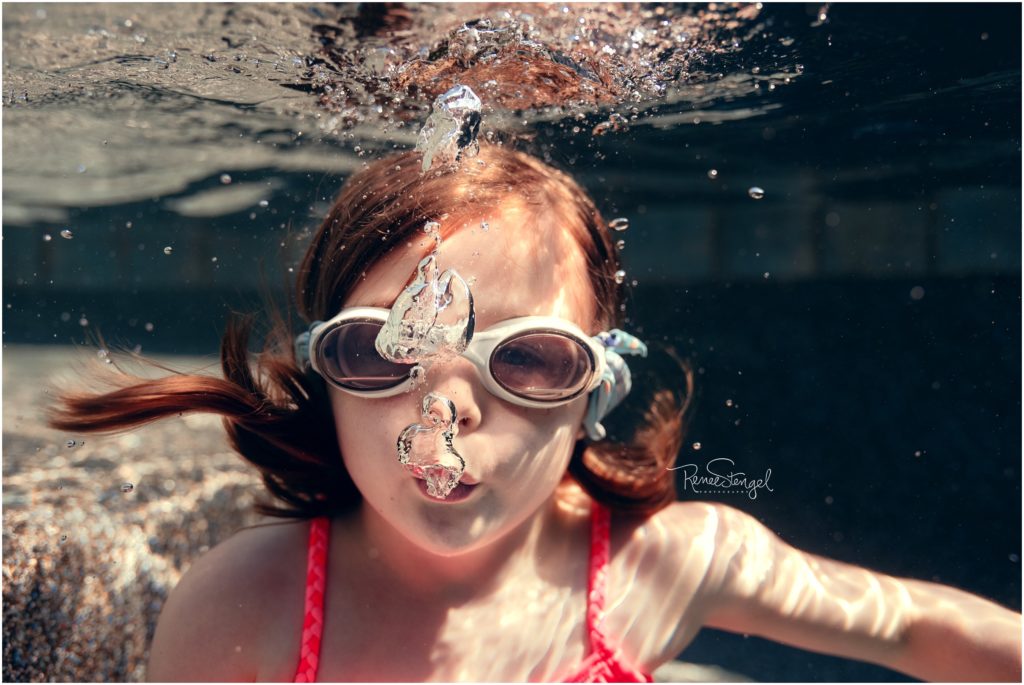 Little Girl Blowing Bubbles Underwater in Goggles