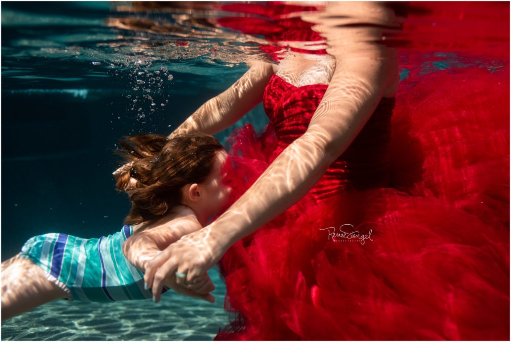 Maternity Photography with Siblings in Charlotte NC as oldest daughter swims to kiss Mama's Baby Belly