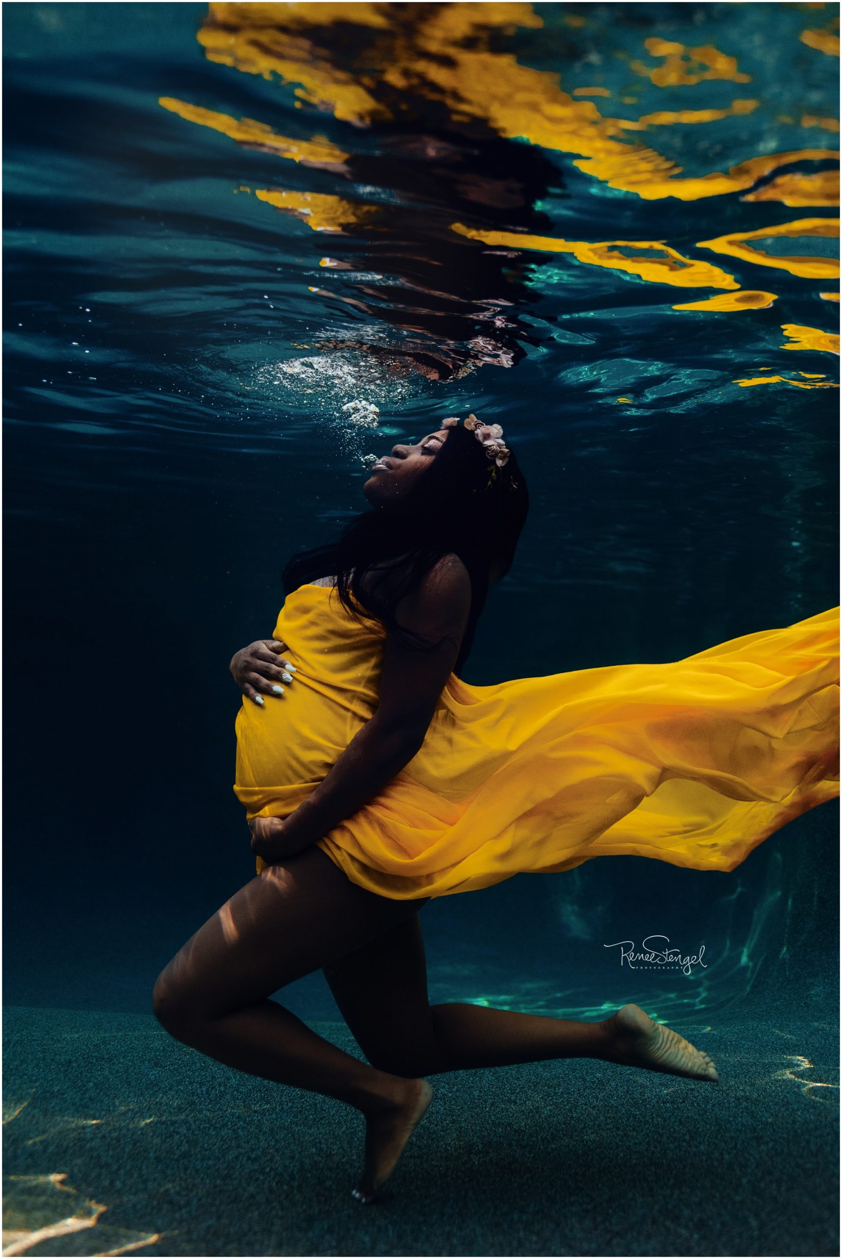 African American submerged Underwater for Maternity Session with yellow fabric
