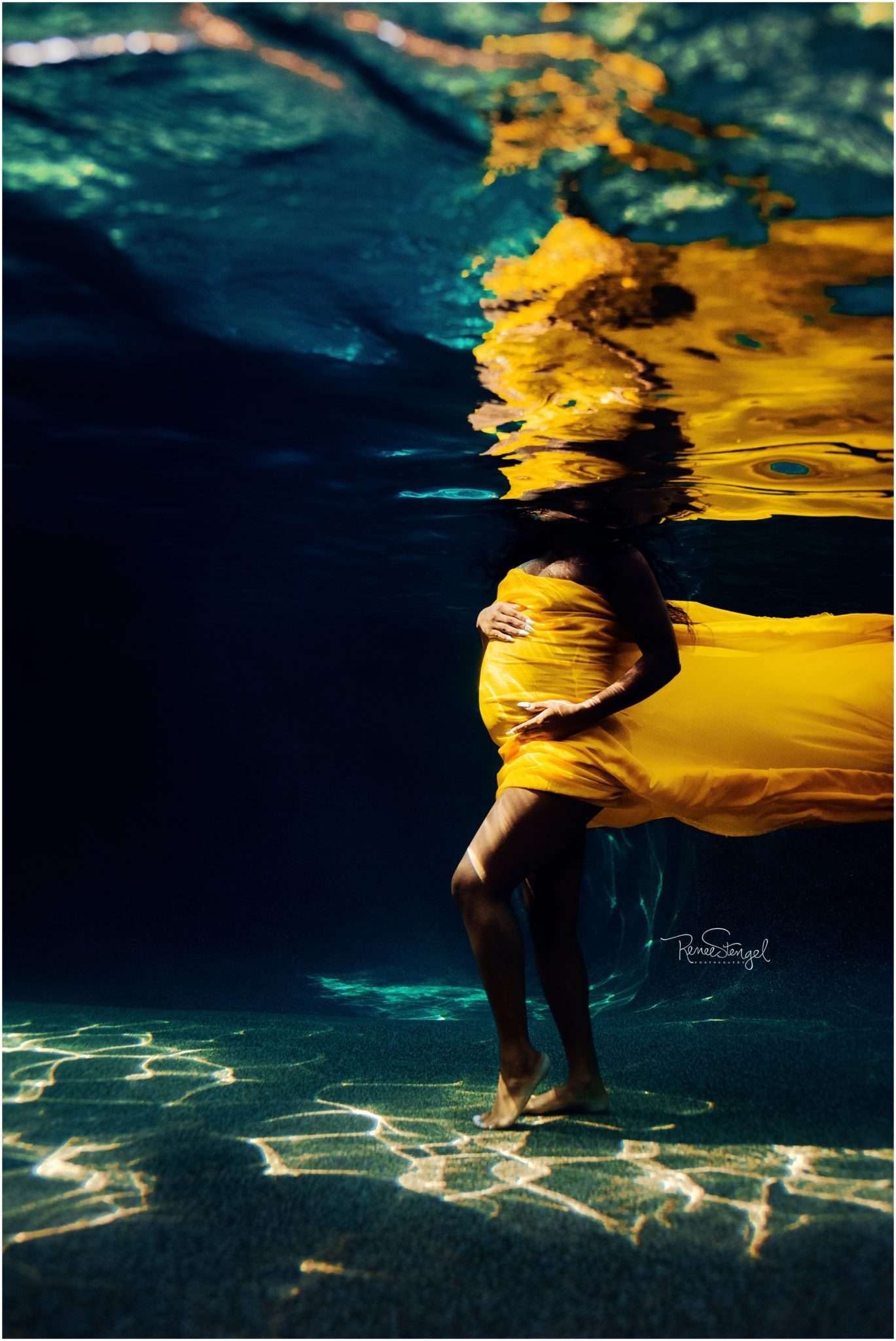 Black Mama to be underwater with yellow fabric hugging belly